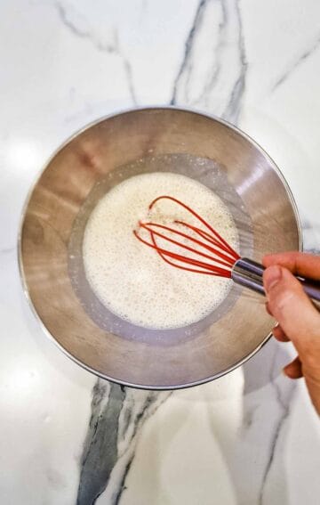 whisking wet ingredients in a large bowl to make vegan pancakes