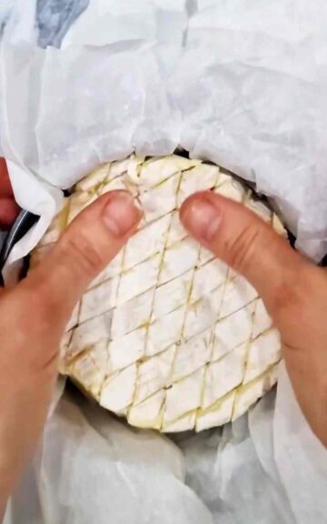 person pushing camembert into a lined baking tin