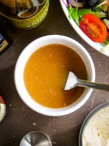 person mixing salad dressing for fish in a ramekin dish