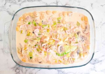 raw pasta in the bottom of a casserole dish with cheese and bacon micture on top before baking in the middle of the oven