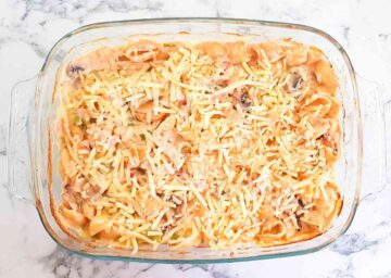 Grated cheddar cheese on top of baked pasta in a cheese sauce before baking again in the oven