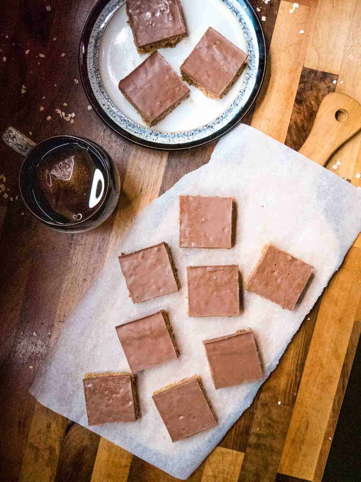 flapjack squares on a lined food platter with a cup of tea and some on a plate on wooden kitchen counter