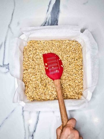 flapjack oat mixture benig pressed into a lined square tin