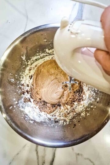 person mixing coffee into buttercream for a coffee and walnut loaf