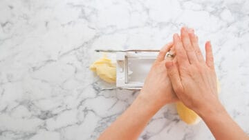 person chipping potatoes using a potato chipper