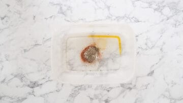 tupperware container with oil, seasoning and spices