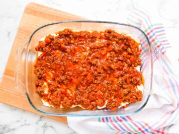 layer of beef ragu on top of white sauce in a lasagne