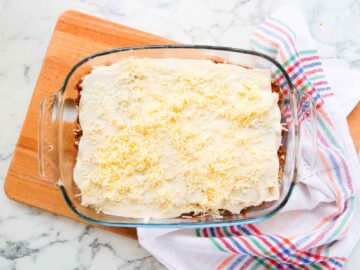 final bechamel sauce and grated cheese topping on top of a lasagne before being baked in the oven