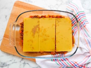 Layer of no boil noodles lasagne sheets on a beef ragu in a glass baking dish