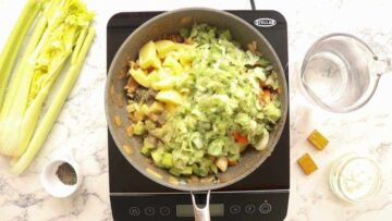 frying diced chicken breast chunks and onions in a large frying pan on induction hob
