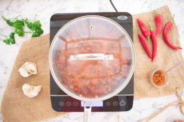 pot of slimming world chili con carne simmering in a lidded pot on induction hob