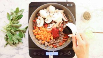 pouring in balsamic vinegar into a frying pan full of vegetables