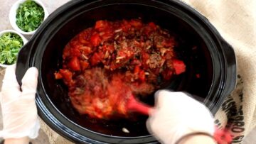 person mixing ingredients together in a slow cooker