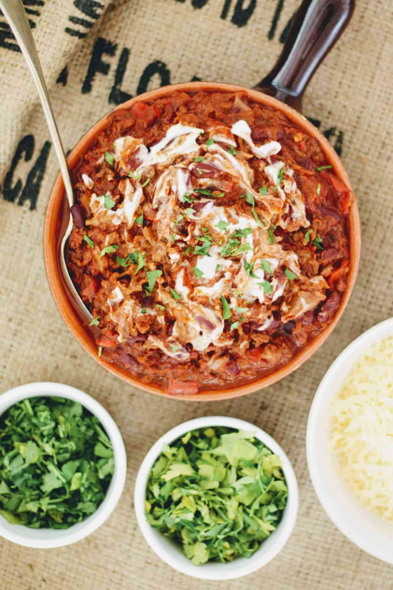 chilli con carne in a terracotta handled spanish pot on hessian sack topped with cream and parsley