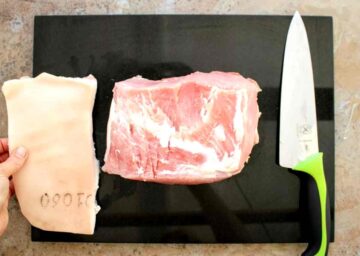 person trimming ewxcess fat off gamon joint with a sharp knife