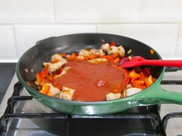 homemade marina sauce being made in a large pan with vegetables over the stove
