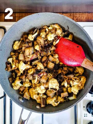 person frying cualiflower and aubergine in a curry spice blend in a large pan