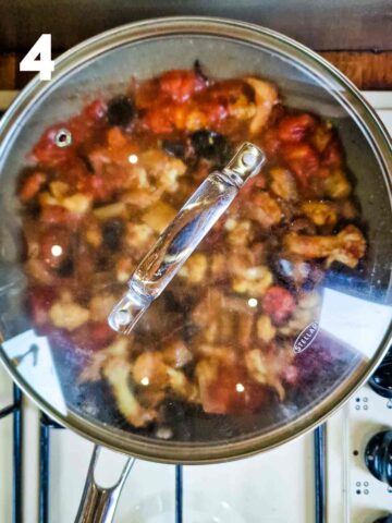 pan with aubergine and caulfilower simmering in a pan with lid on