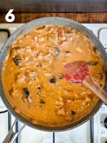 person stirring a curried coconut vegan sauce with aubergine and cauliflower in a pan