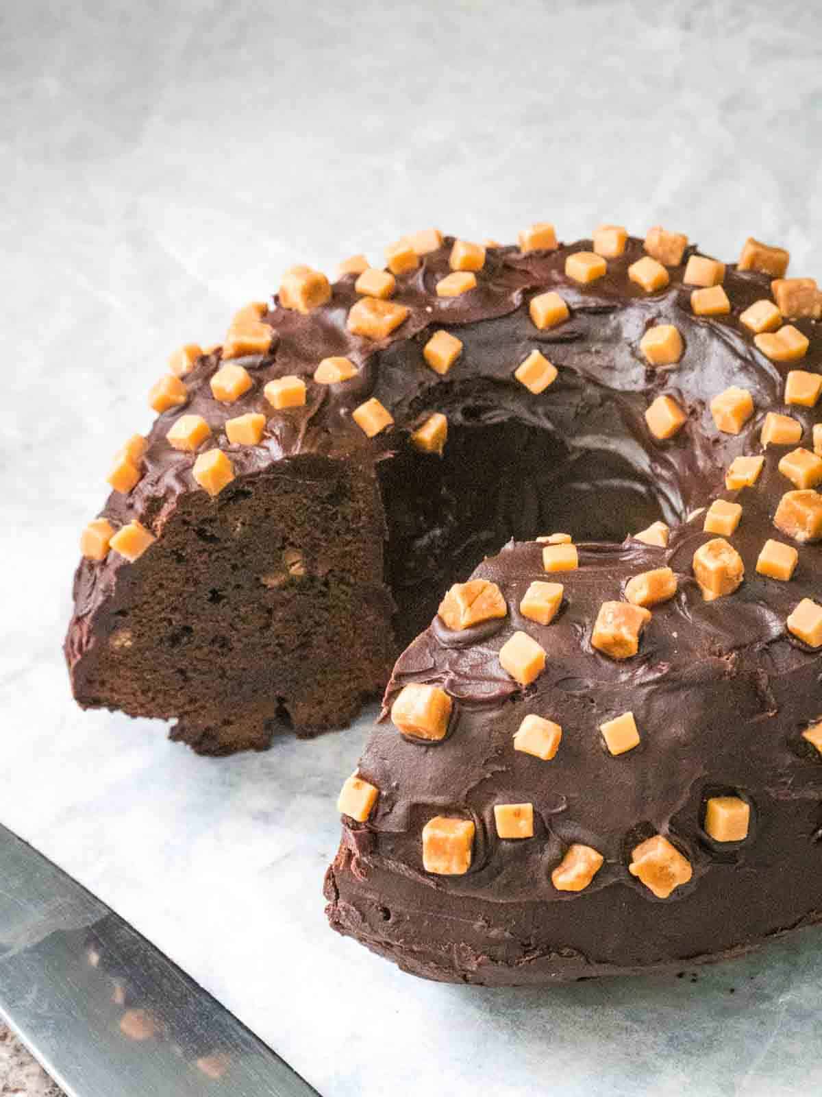 Section cut out from brownie bundt cake with chocolate icing and fudge on top