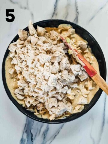 Person mixing diced cooked chicken into an easy cold creamy curry sauce
