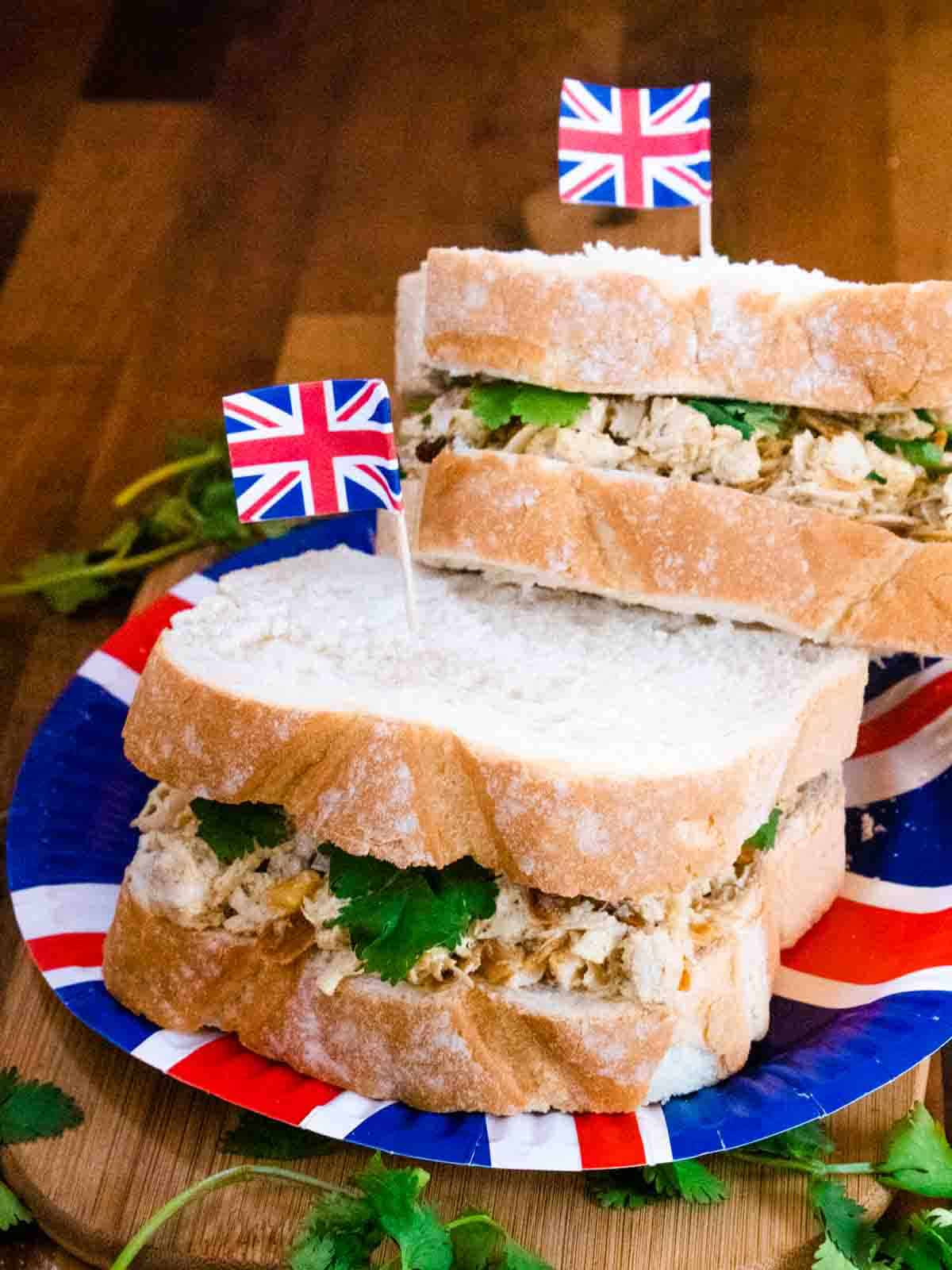 Stack of Coronation chicken party sandwiches on Union Jack paper plates with cocktail stick flags