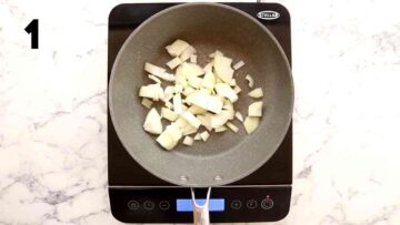 person sauteeing onions in frying pan on induction hob
