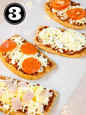 pizza toppings like pepperoni, ham and pineapple, cheese and tomato on pitta breads before baking in the oven