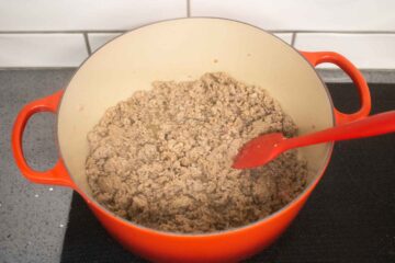 browning minced lamb in a large Le Creuset cast iron casserole dish