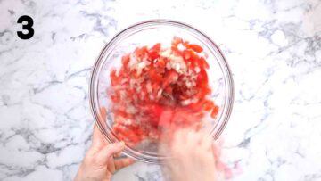 person stirring an easy homemade salsa in a large glass bowl