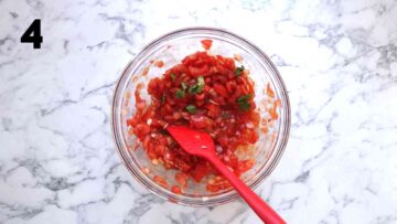 fresh coriander added to a tomato salsa in a large glass bowl