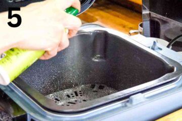 person spraying air fryer basket with cooking oil spray for non stick