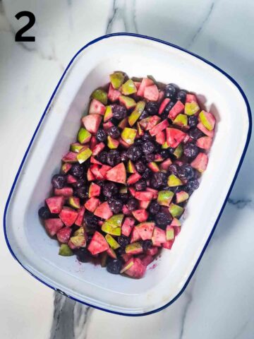 mixed apple and berries in a large white and blue enamel baking dish