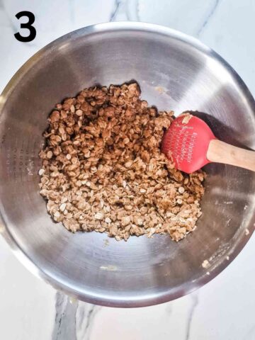 person mixing apple crumble topping with oats in a stainless steel mixing bowl