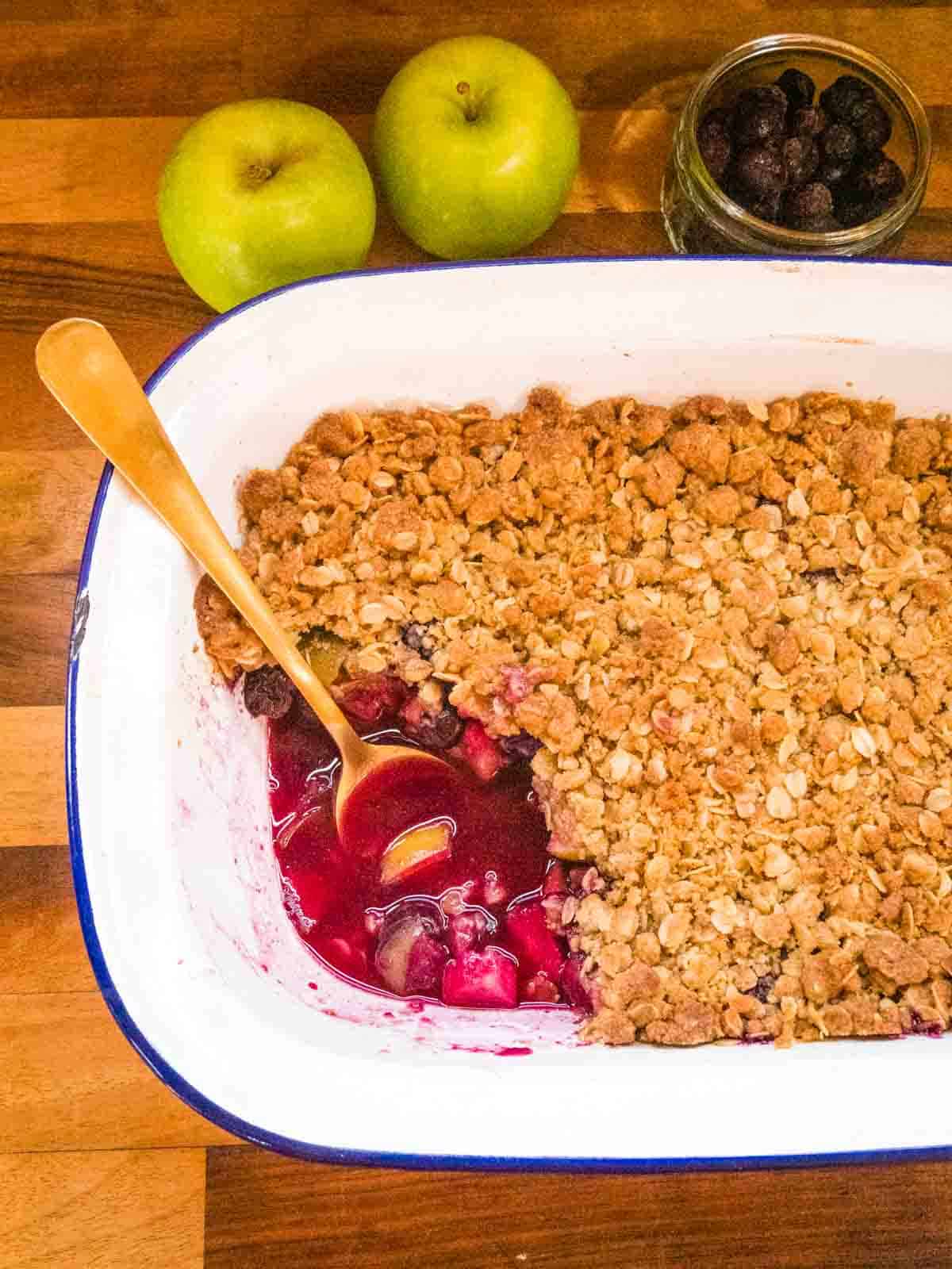 close up of a gold spoon in baked apple and blueberry crisp