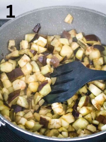 person frying diced aubergine in a large frying pan on the stovetop