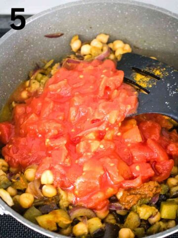 person stirring canned tomatoes and puree to make a curry aubergine recipe
