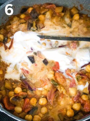 person stirring coconut milk into a vegan curried aubergine and chickpea recipe