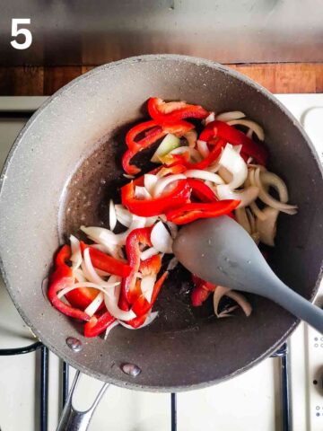 person sauteeing sliced onions and red peppers in a large wok with oil