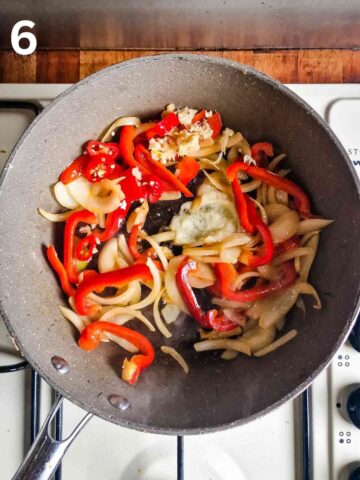 garlic, chilli and ginger added to a large frying pan with stir fried onions and peppers