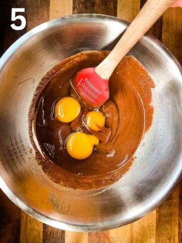 person stirring eggs, vanilla extract and coffee mixture into brownie batter
