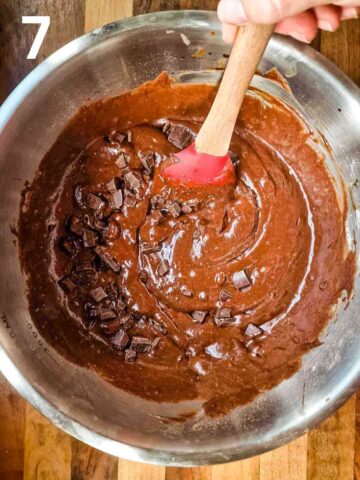 person folding in dark chocolate chips into coffee chocolate brownie batter