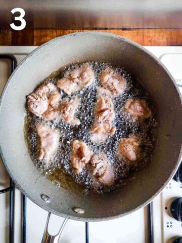 deep frying chopped chicken thighs in a deep pan on stove top full of vegetable oil