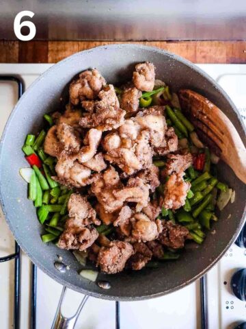 person mixing crispy Chinese chicken in a pan with fried vegetables