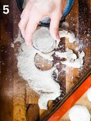 person cutting scone shapes with a glass dipped into more oatflour on a dusted worktop