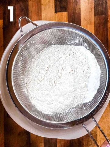 person sifting self raising flour and other dry ingredients into a large mixing bowl