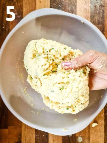 person bring wet scone dough together with their hands