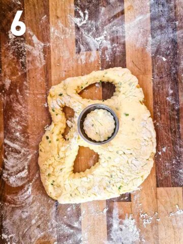 person cutting scones with a scone pastry cutter on floured kitchen worktop