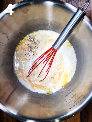person mixing whisked eggs with milk and seasoning