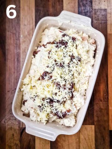 cheese, egg custard and diced stale bread in a ceramic baking dish topped with grated cheddar cheese before baking in oven